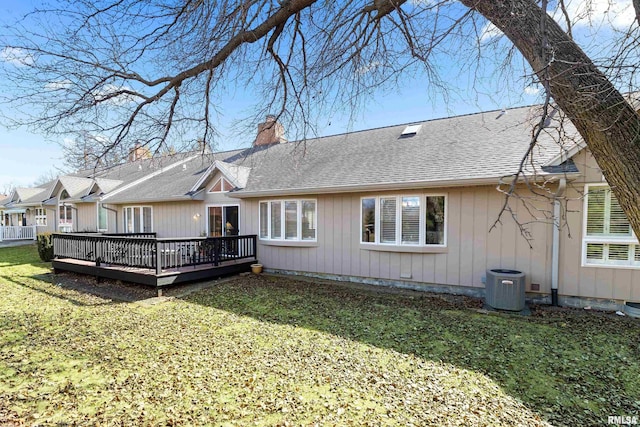 rear view of house with a deck, cooling unit, a lawn, and a chimney