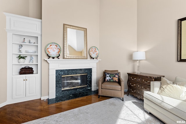 living room with baseboards, wood finished floors, and a high end fireplace