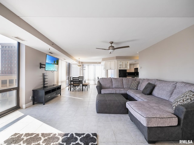 living area featuring light tile patterned floors, visible vents, and ceiling fan