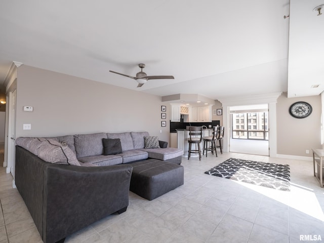 living room featuring baseboards, light tile patterned flooring, and a ceiling fan