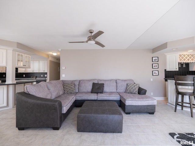 living area with light tile patterned flooring, baseboards, and a ceiling fan