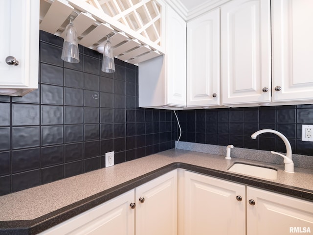 kitchen with dark countertops, decorative backsplash, white cabinets, and a sink