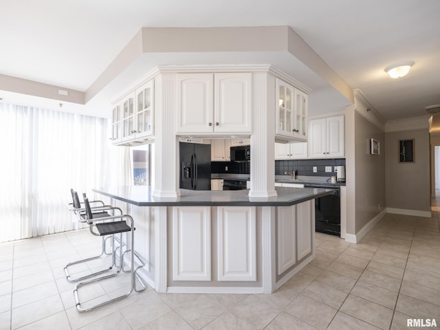 kitchen with dark countertops, a breakfast bar area, black appliances, and glass insert cabinets