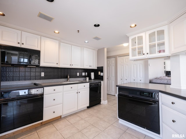 kitchen featuring visible vents, glass insert cabinets, decorative backsplash, black appliances, and a sink