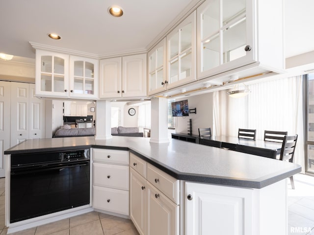 kitchen with black oven, white cabinetry, recessed lighting, light tile patterned flooring, and glass insert cabinets