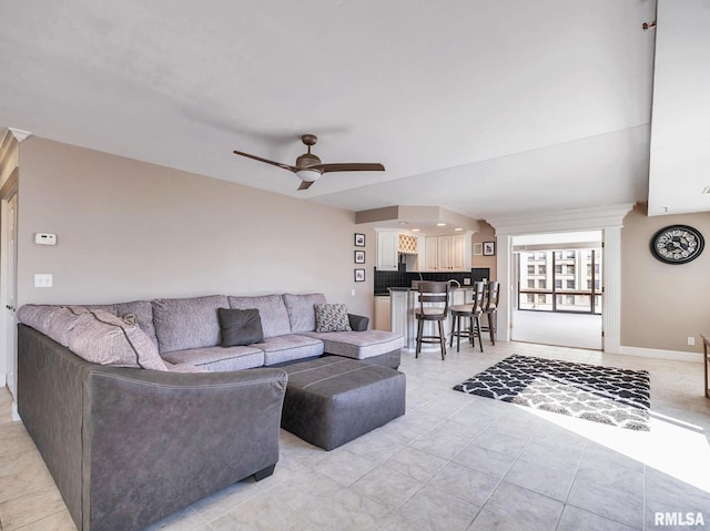 living area featuring light tile patterned floors, baseboards, and ceiling fan