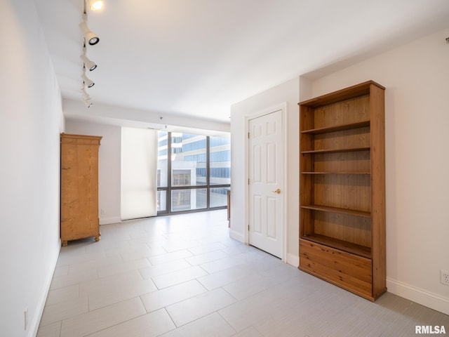 unfurnished room featuring track lighting, baseboards, and expansive windows