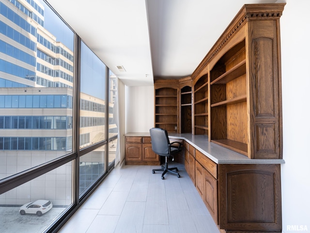 office space with visible vents, floor to ceiling windows, and built in study area