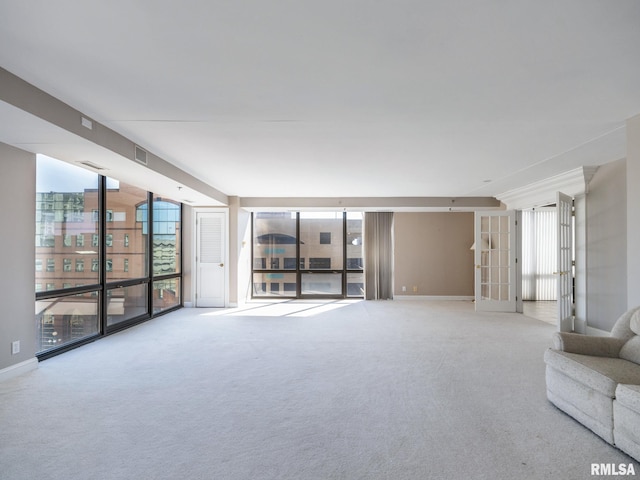 unfurnished living room featuring a wall of windows, french doors, visible vents, and carpet floors