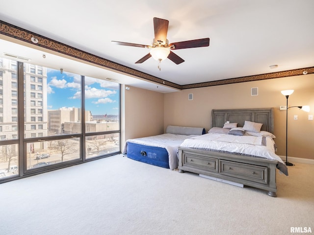 bedroom with visible vents, a view of city, carpet, baseboards, and ceiling fan