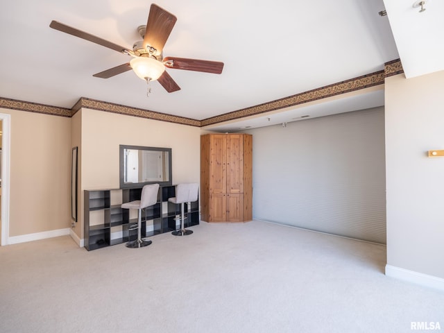 interior space with baseboards, a ceiling fan, and carpet flooring