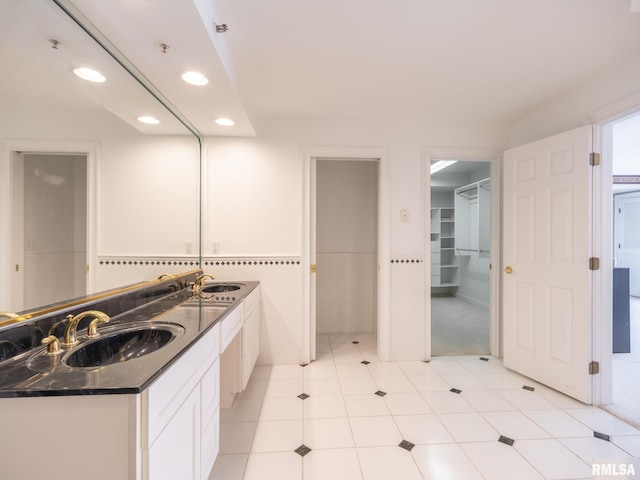 full bathroom with double vanity, recessed lighting, and a sink