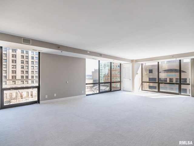 unfurnished room featuring visible vents, floor to ceiling windows, baseboards, and carpet floors