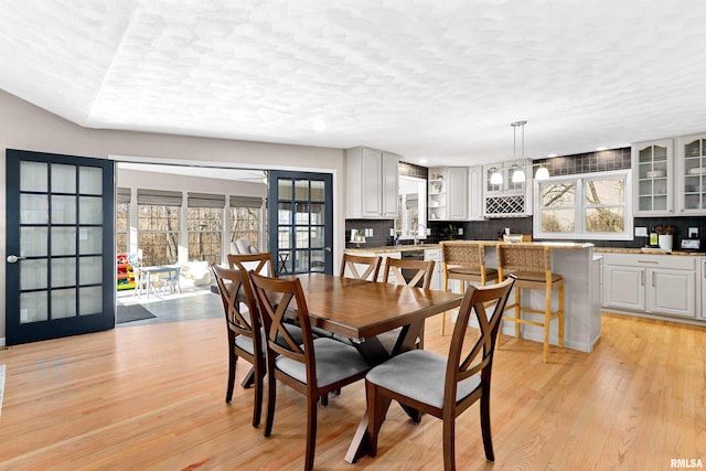 dining space featuring plenty of natural light, light wood finished floors, and a textured ceiling