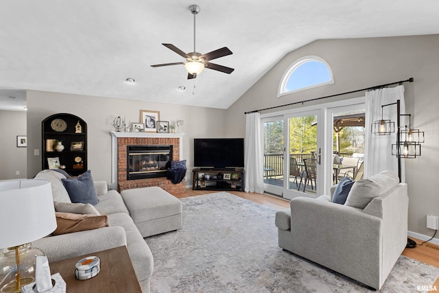 living area featuring wood finished floors, baseboards, a fireplace, ceiling fan, and vaulted ceiling