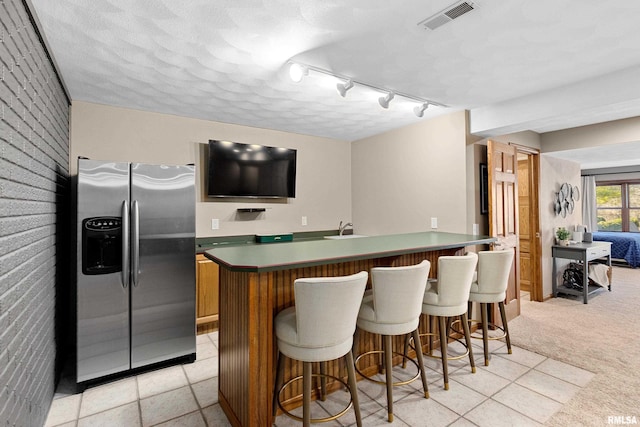 kitchen featuring a sink, visible vents, a breakfast bar area, and stainless steel fridge with ice dispenser