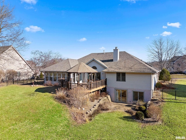 back of property with a sunroom, a lawn, a chimney, and fence