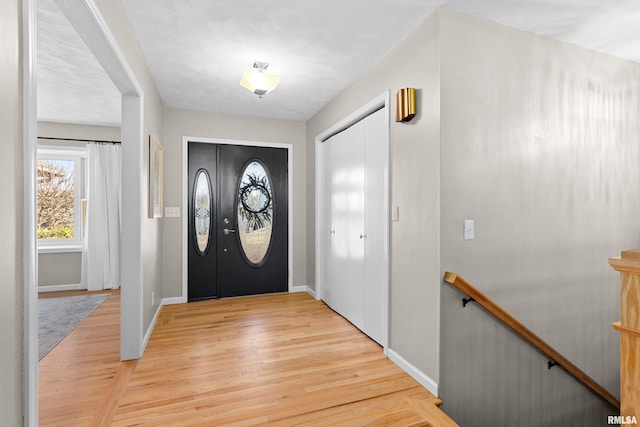 foyer entrance with light wood-style flooring and baseboards