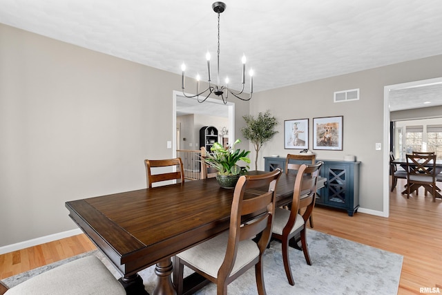 dining area featuring a notable chandelier, visible vents, light wood-type flooring, and baseboards