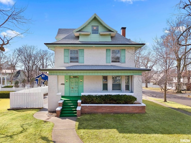 american foursquare style home with stucco siding, a front yard, and fence