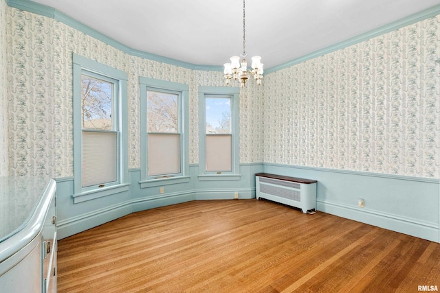 spare room featuring wallpapered walls, radiator, light wood-style floors, and a wainscoted wall