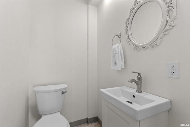 bathroom featuring toilet, vanity, and baseboards