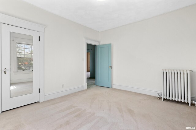 empty room with radiator heating unit, baseboards, and carpet floors