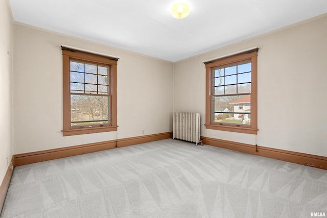 unfurnished room with light carpet, plenty of natural light, radiator, and baseboards