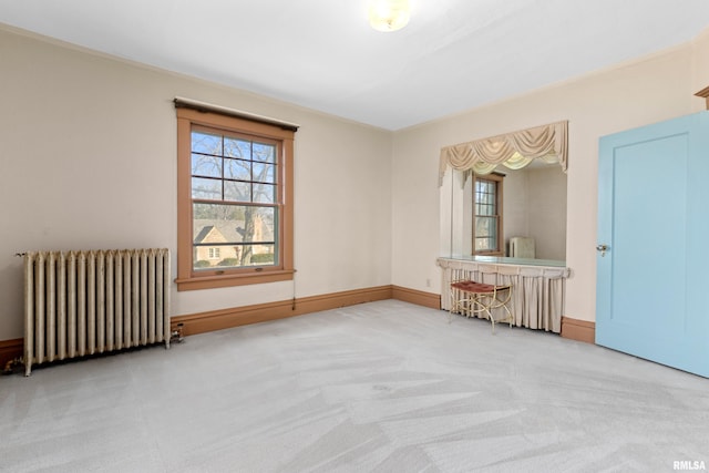 carpeted spare room featuring radiator and baseboards