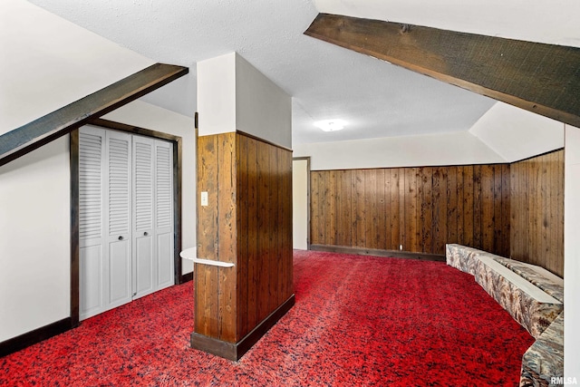 bonus room with carpet, wooden walls, and a textured ceiling