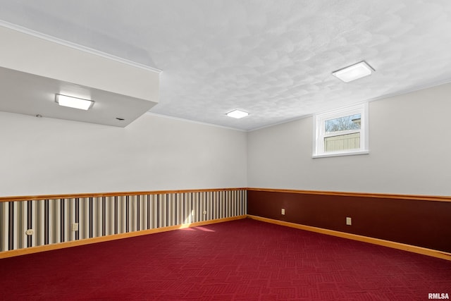 carpeted empty room featuring a textured ceiling, baseboards, and ornamental molding