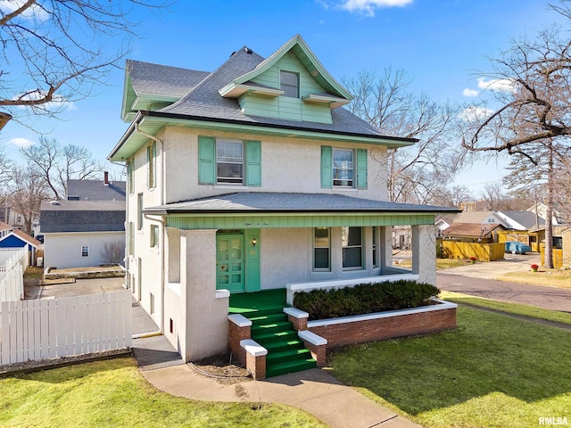 traditional style home with stucco siding, a porch, a front lawn, and fence