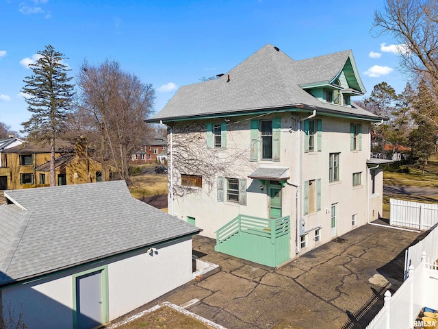 rear view of property with a patio, roof with shingles, and stucco siding