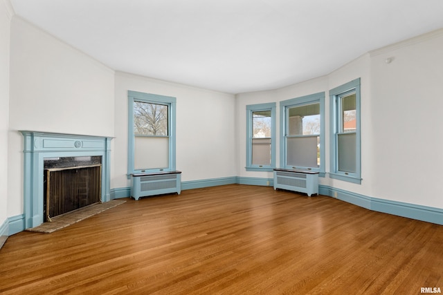 unfurnished living room with light wood-style floors, radiator, and a high end fireplace