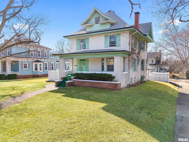 american foursquare style home featuring a front lawn, covered porch, a chimney, and fence