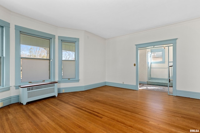 unfurnished room with a wealth of natural light, crown molding, radiator heating unit, and wood finished floors