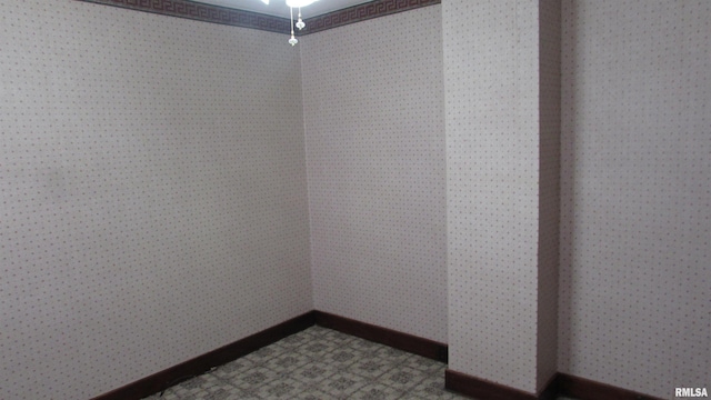 spare room featuring wallpapered walls and baseboards