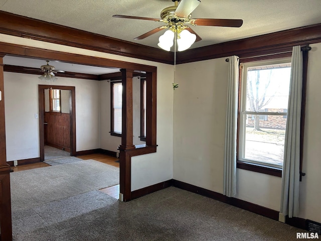 empty room with ceiling fan, baseboards, a textured ceiling, and ornamental molding