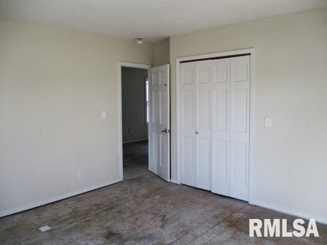 unfurnished bedroom featuring unfinished concrete floors, baseboards, and a closet