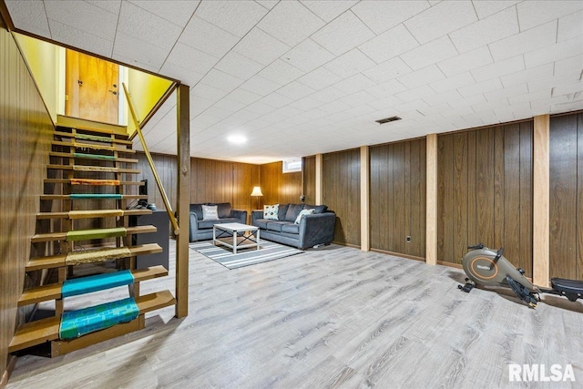 living room featuring stairs, wood finished floors, visible vents, and wood walls