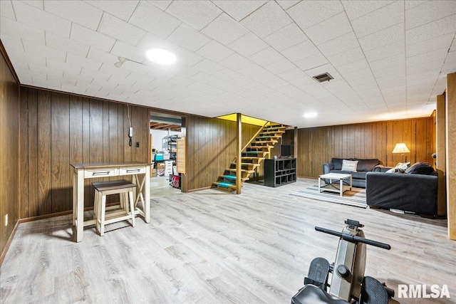 workout room featuring visible vents, baseboards, wood finished floors, and wood walls