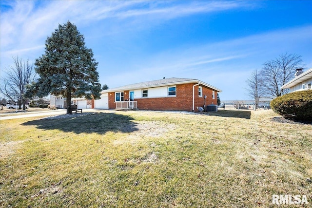 exterior space featuring a yard, brick siding, a garage, and central AC