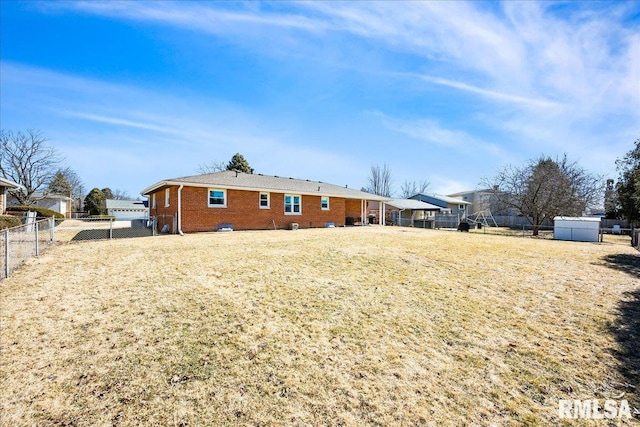 back of house featuring a fenced backyard, brick siding, and a lawn