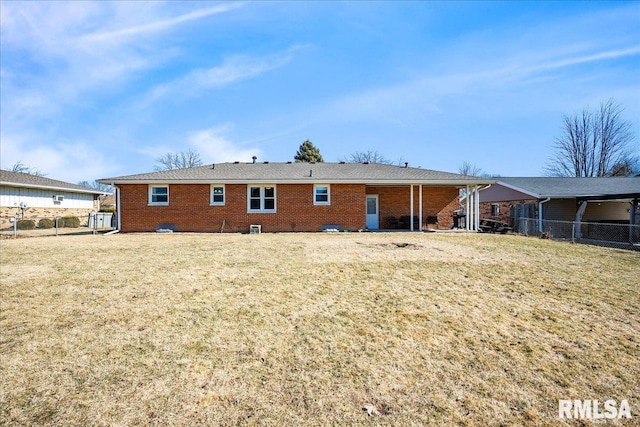 back of property featuring brick siding, a lawn, and fence