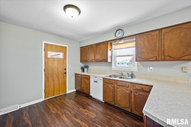 kitchen featuring visible vents, dark wood finished floors, white dishwasher, a sink, and light countertops