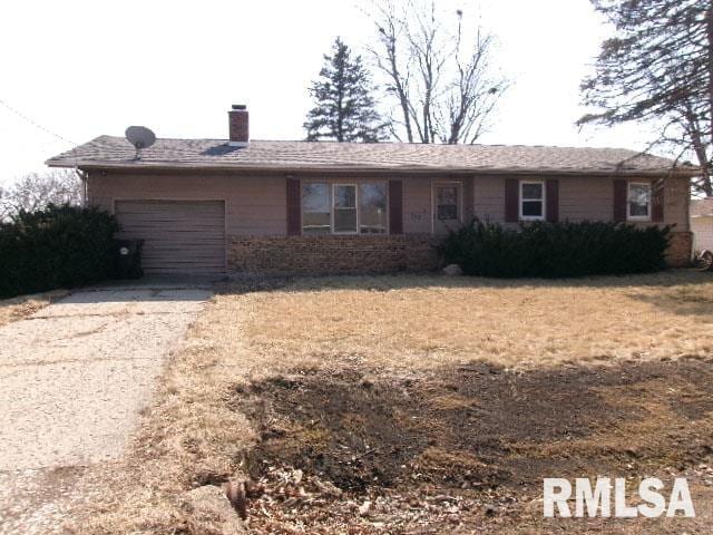 ranch-style home featuring aphalt driveway, a garage, and a chimney