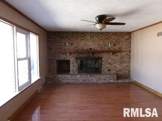 unfurnished living room featuring wood finished floors, a fireplace, and a wealth of natural light