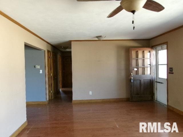 spare room with baseboards, wood finished floors, and crown molding