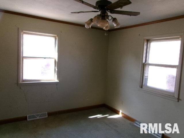 unfurnished room with visible vents, baseboards, ornamental molding, and carpet flooring