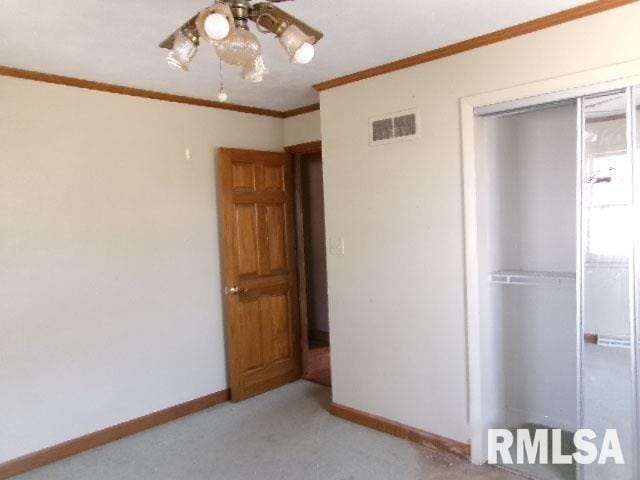 unfurnished bedroom with visible vents, ornamental molding, a closet, baseboards, and light colored carpet